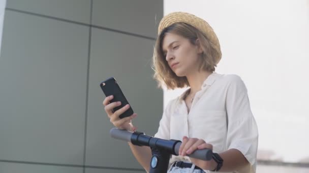 Dolly movimento da mulher está usando smartphone após passeio em scooter elétrico — Vídeo de Stock