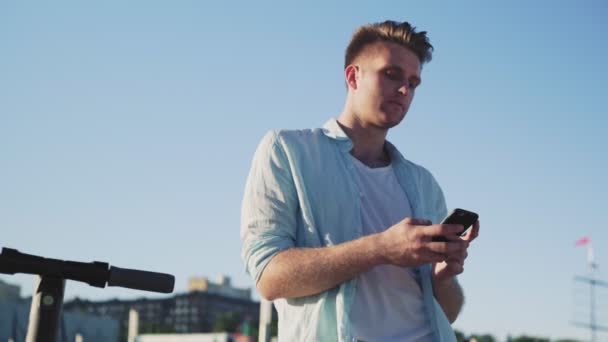 Mann benutzt Smartphone nach Fahrt auf Elektro-Tretroller — Stockvideo