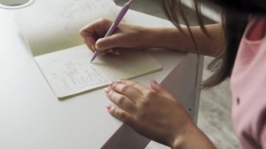 Kadın defterini kapat. Not defterine kalemle not yaz.