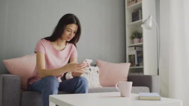 Beyaz tenli genç bir kadının akıllı telefonuna tıklaması, kaydırması ve yazması.