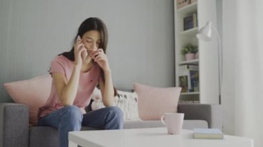 Güzel bir kadın evde cep telefonuyla konuşur.