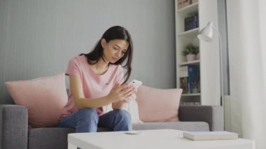 Akıllı telefonunu kaydıran genç bir kadın. Genç bir kadın akıllı telefonuyla sosyal medyayı tarıyor..