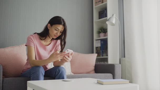 Young Woman Scrolling her Smartphone. Young woman scrolls the social media feed using her smartphone. Relaxed woman checking email and typing on cellphone at home — Stock Video