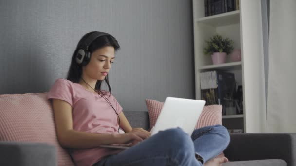 Freelancer jovem sério trabalhando em freelancer de casa digitar e-mail no laptop, menina focada usando o computador para estudar on-line em casa sentado no sofá — Vídeo de Stock