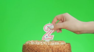 İki numaralı doğum günü mumunu lezzetli bir pastaya koyuyorum, yeşil ekran 2.
