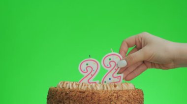 22 numaralı doğum günü mumunu lezzetli bir pastaya koyuyorum, yeşil ekran 22.