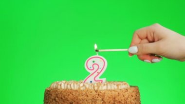 İki numaralı doğum günü mumunu yakıyorum lezzetli bir kekin üzerinde, yeşil ekran 2
