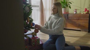 Güzel bir kadın Noel ağacını oyuncaklarla süslüyor.