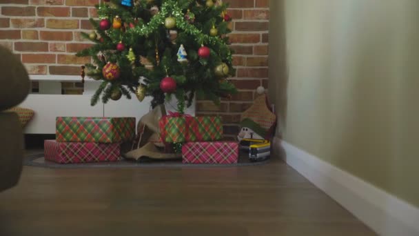 Weihnachtsbaum mit dekorativem Licht. Geschenkboxen und Spielzeug-Dampfmaschine auf dem Boden. — Stockvideo