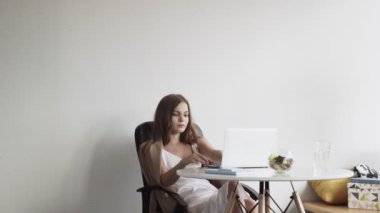 İş kadını iş yerinde defter üzerinde çalışıyor. Genç adam bir kadının işlerini kontrol etmeye geldi.