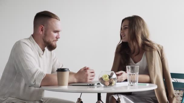 Двое счастливых коллег разговаривают и флиртуют, сидя в столовой в офисе во время кофе-брейка — стоковое видео