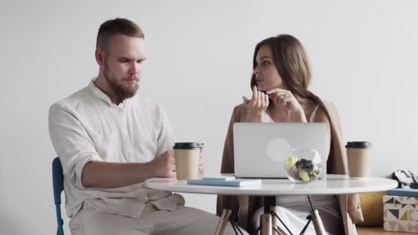 Dwoje młodych ludzi omawia i przygotowuje kontrakt. To spotkanie biznesowe. Mężczyzna i kobieta siedzą w kawiarni przy stole podczas przerwy. — Wideo stockowe