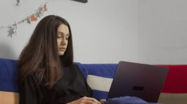 Kanepede bilgisayarında çalışan çekici bir kadın.