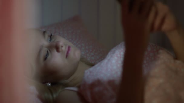 Närbild av ung attraktiv kvinna som ligger på sängen i vandrarhemsrummet och använder smartphone — Stockvideo