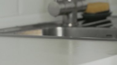 Sarı eldivenli ev kadını masayı beyaz bez ve deterjanla yıkıyor..