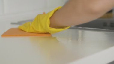 Sarı eldivenli ev kadını, orage bezi ile masayı temizle.