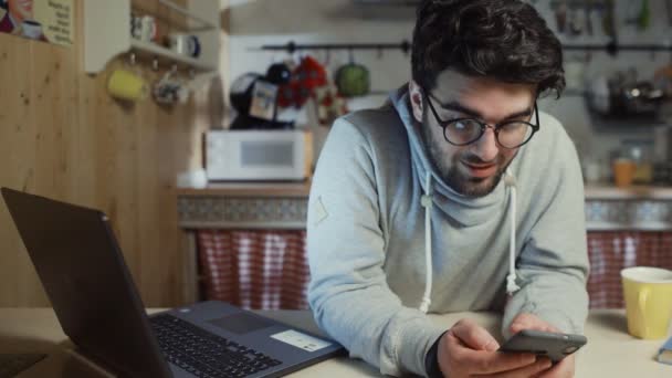 Giovane uomo felice utilizzando smartphone in cucina a casa di notte — Video Stock