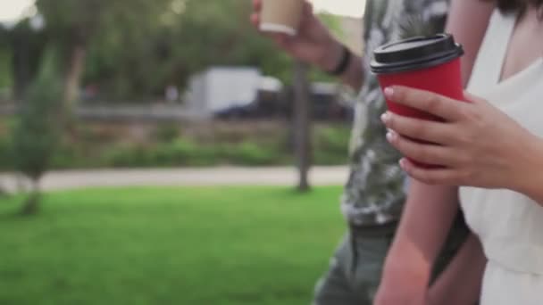 Gros plan de jeunes couples charmants se promènent dans le parc d'été, boivent du café et discutent — Video