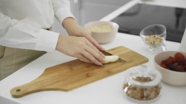 Kız mutfakta muz keserek temizledi.