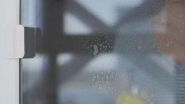 Jeune femme en gants jaunes fenêtre de lavage avec chiffon bleu et détergent . — Video