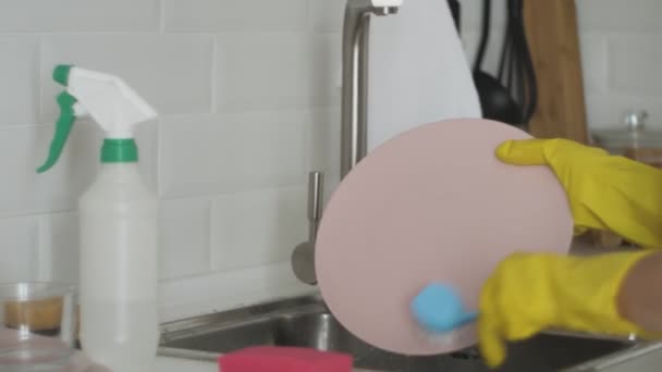 Young woman with gloves washing dishes in the kitchen — Stock Video