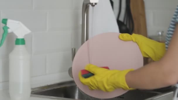 Jonge vrouw met handschoenen afwassen in de keuken — Stockvideo