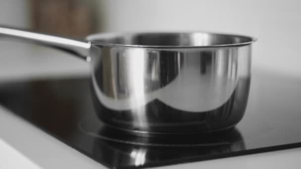 Woman takes off saucepan from induction cooker — Stock Video