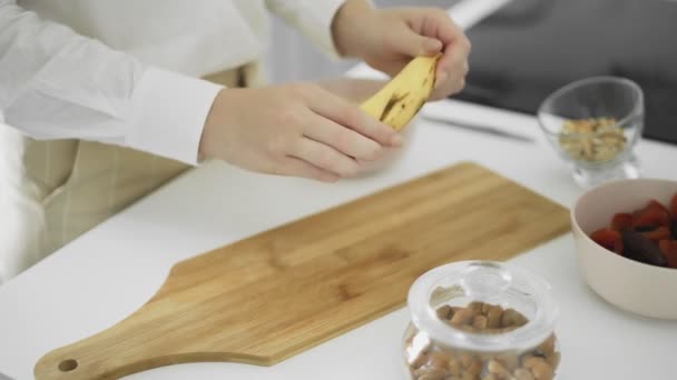 The girl cleans the banana peel in the kitchen — Stock Video