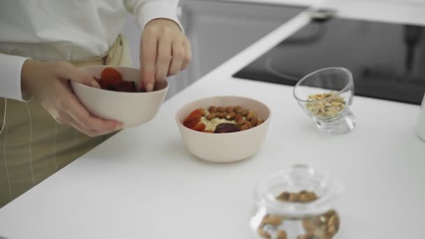 Ceramic bowl of oatmeal porridge with banana, date, dried apricots, nuts. Healthy breakfast and diet food. — Stock Video