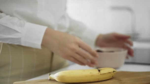 Close up de menina limpa a casca de banana na cozinha — Vídeo de Stock