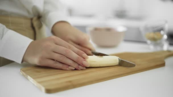 Close up de menina cortada banana limpa na cozinha — Vídeo de Stock