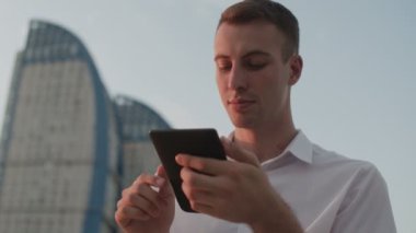 Açık havada beyaz kısa kitap okuyan genç adam.