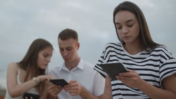 Estudantes engraçados estão lendo ebooks ao ar livre — Vídeo de Stock