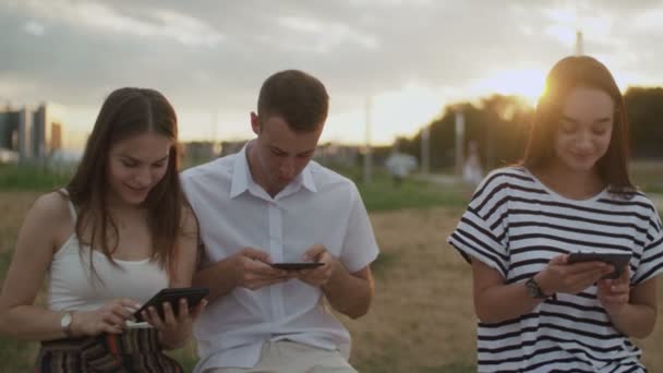 Studenter läser e-böcker i parken — Stockvideo