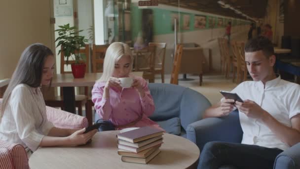 Amigos están tomando café y leyendo libros electrónicos en la cafetería — Vídeos de Stock