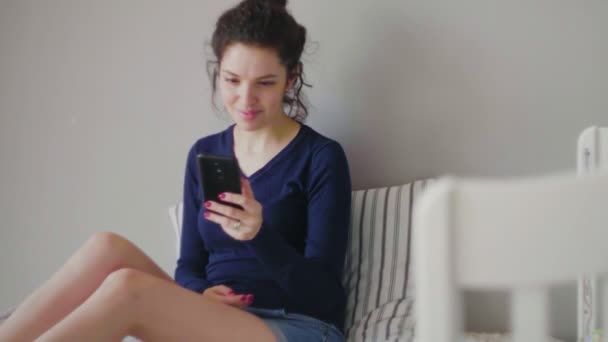 Женщина делает покупки в Интернете на своей кровати, используя свой телефон — стоковое видео