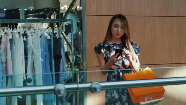 Asiatin steht mit Smartphone in Einkaufszentrum. — Stockvideo