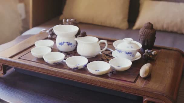 Utensílios de cerâmica para cozinhar chá chinês fica em uma mesa de madeira — Vídeo de Stock
