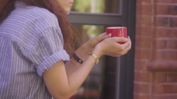 Vista lateral de la hermosa mujer está tomando café fuera. Una chica está tomando té afuera. . — Vídeo de stock