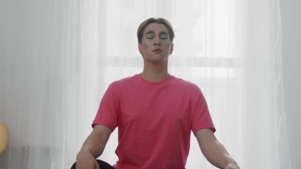 Pria homoseksual transgender muda dengan makeup melakukan latihan napas yoga — Stok Video