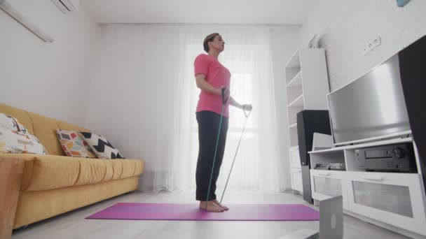 Young transgender homosexual man with makeup exercising with resistance band — Stock Video