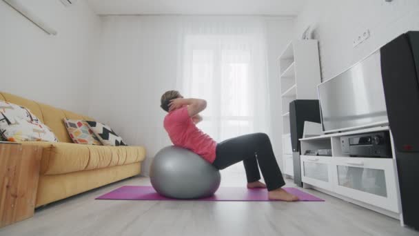 Ung transsexuell homosexuell man med make up gör abs crunch motion på fitball hemma — Stockvideo