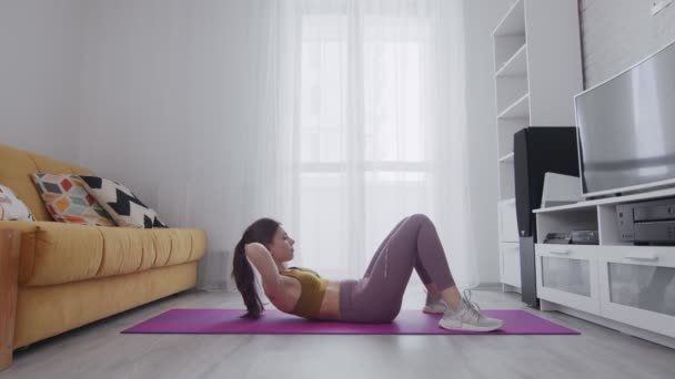 Young beautiful woman with tattoo doing abs crunch exercise on mat — Stock Video