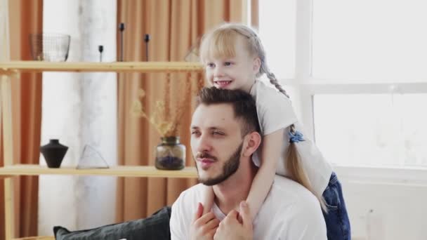 Glücklicher Familienvater mit süßer kleiner lustiger Tochter zu Hause. Vatertagskonzept — Stockvideo