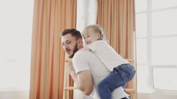 Feliz família amoroso pai dando bonito pouco engraçado criança filha piggyback passeio girando em casa. Conceito de dia dos pais — Vídeo de Stock