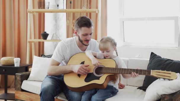 어린 아버지는 딸에게 집에서 기타치는 법을 가르친다 — 비디오