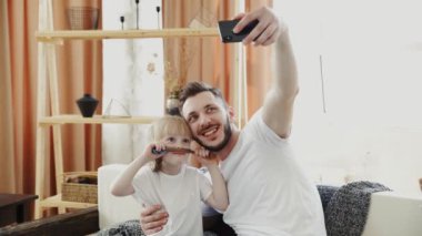 Genç baba ve kızı evde selfie çekiyor.