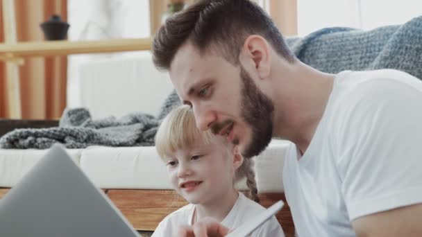 Feliz padre pasando tiempo con su pequeña hija. Están mirando el cuaderno. — Vídeos de Stock