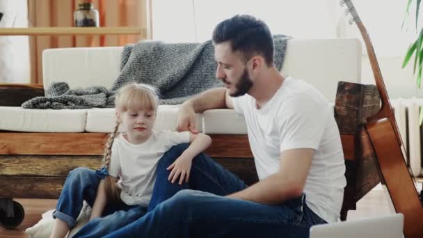 Glücklicher Vater, der Zeit mit seiner kleinen Tochter verbringt. Sie sitzen auf dem Boden und unterhalten sich — Stockvideo