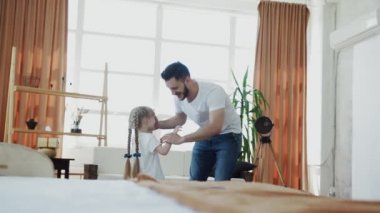 Genç baba küçük kızını döndürüyor.